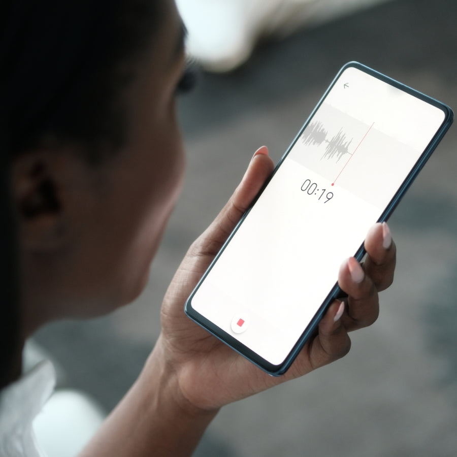 Persona usando un smartphone con la app Plaud, mostrando una grabación de audio con forma de onda y temporizador.