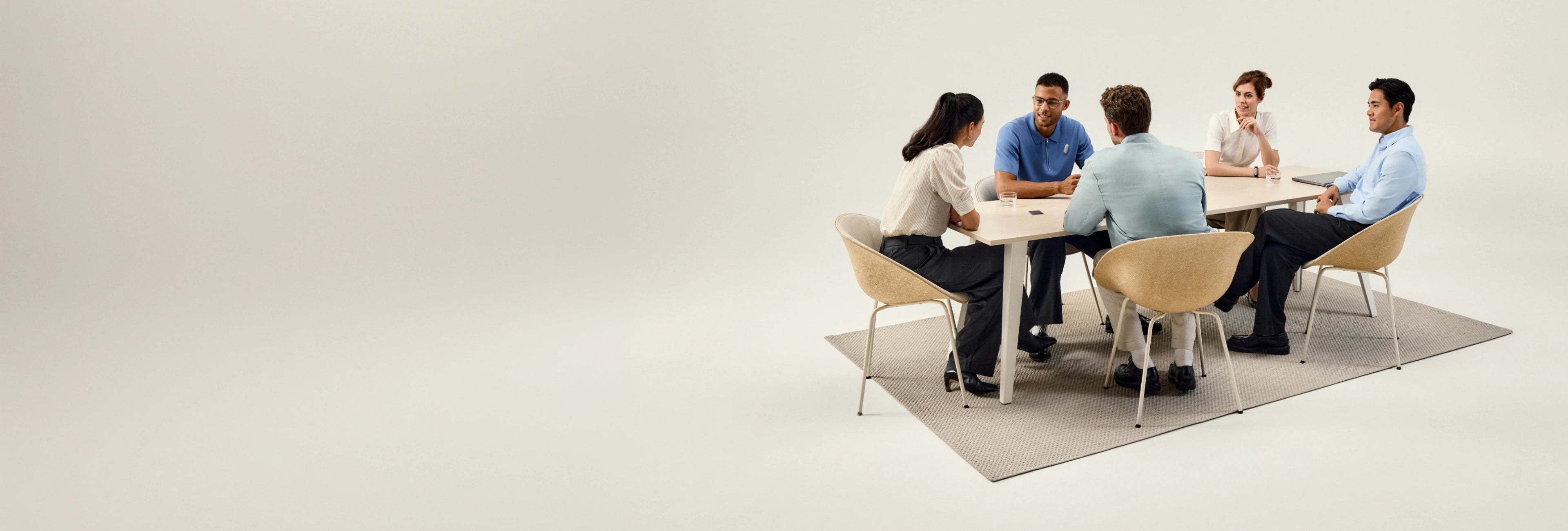 Cinco personas sentadas alrededor de una mesa, participando en una reunión o discusión.