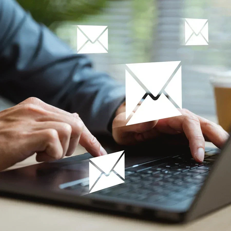 Manos escribiendo en un portátil con iconos de correo electrónico flotando, simbolizando comunicación digital.