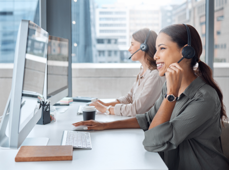 Agentes de servicio al cliente sonrientes con auriculares en un centro de llamadas moderno.