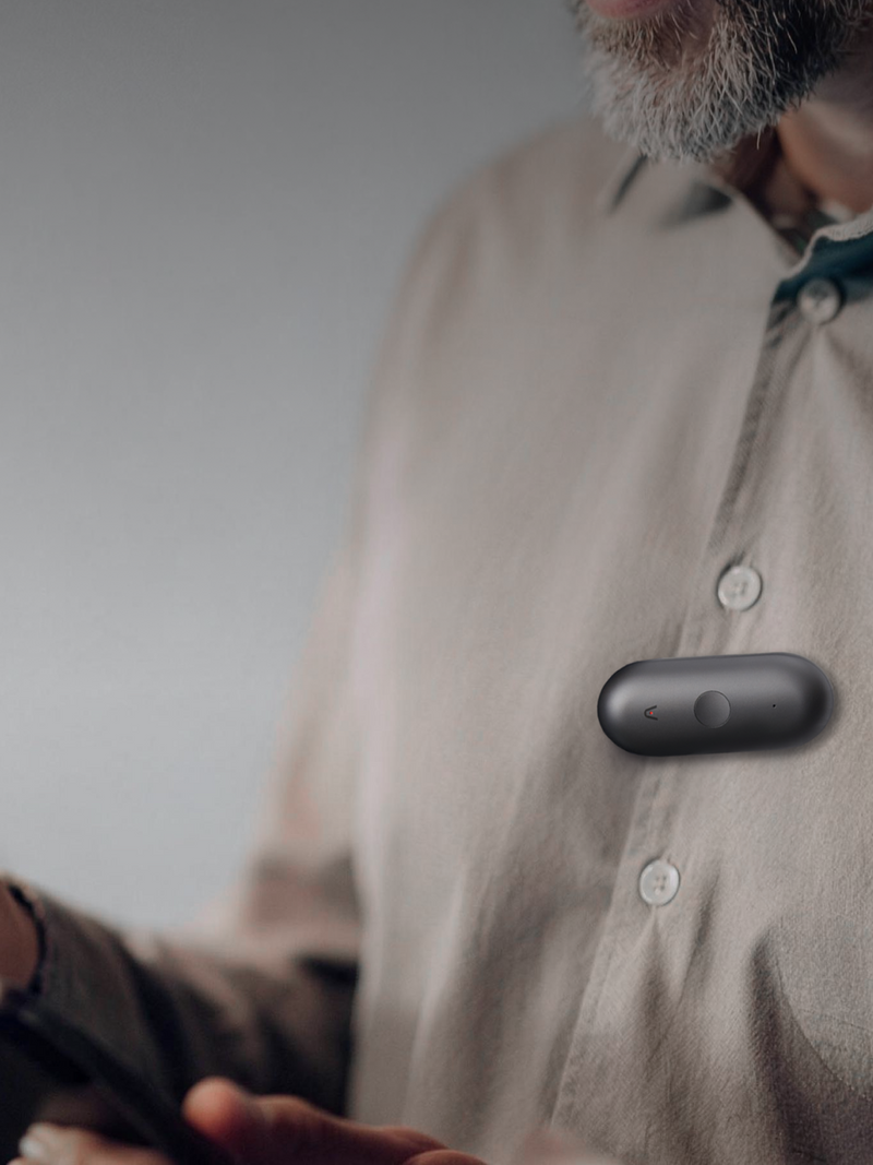 Plaud NotePin S negro sujeto a la camisa de un hombre, capturando audio discretamente.